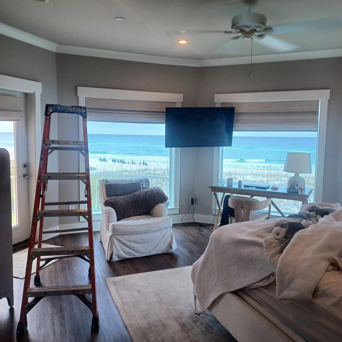 Bedroom with soft gray walls and a ladder, overlooking the beach