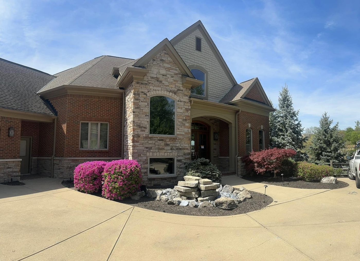 Brick and stone home with freshly painted tan trim and gutters
