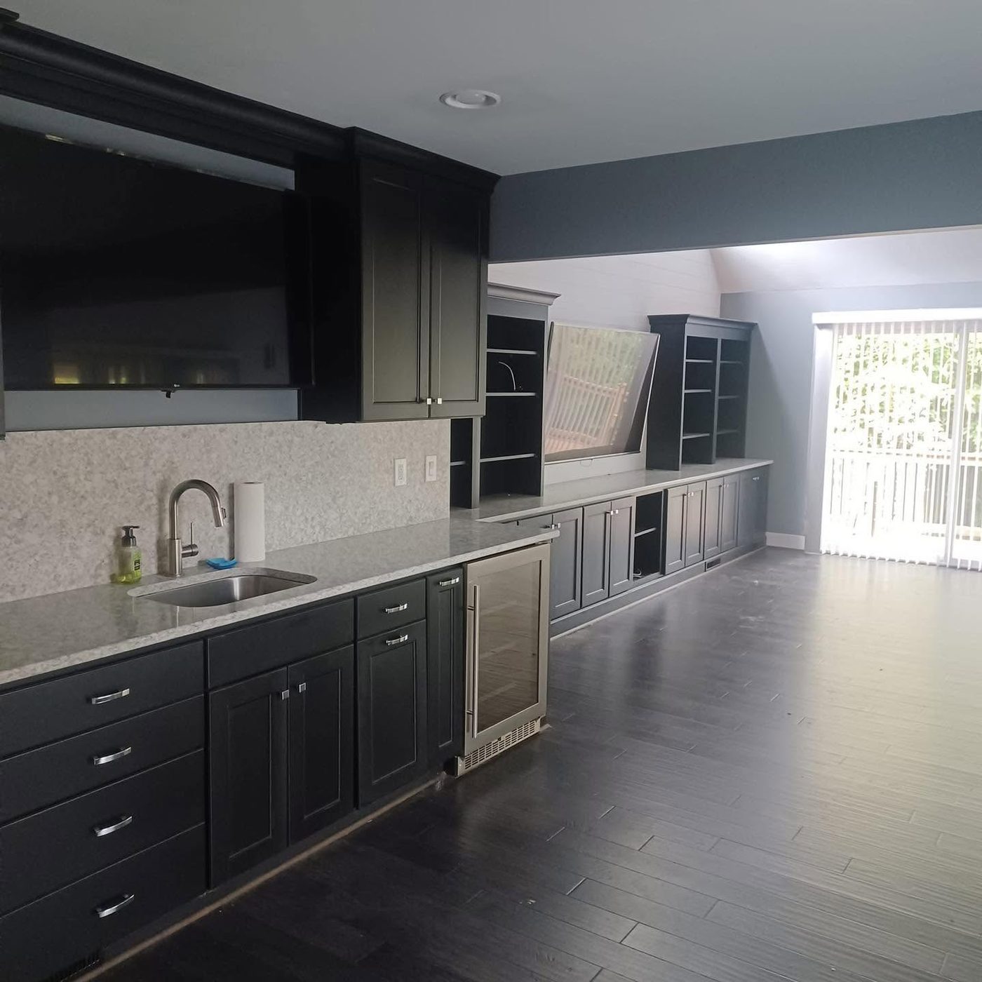 Dark charcoal cabinets and built-in shelving along a wet bar