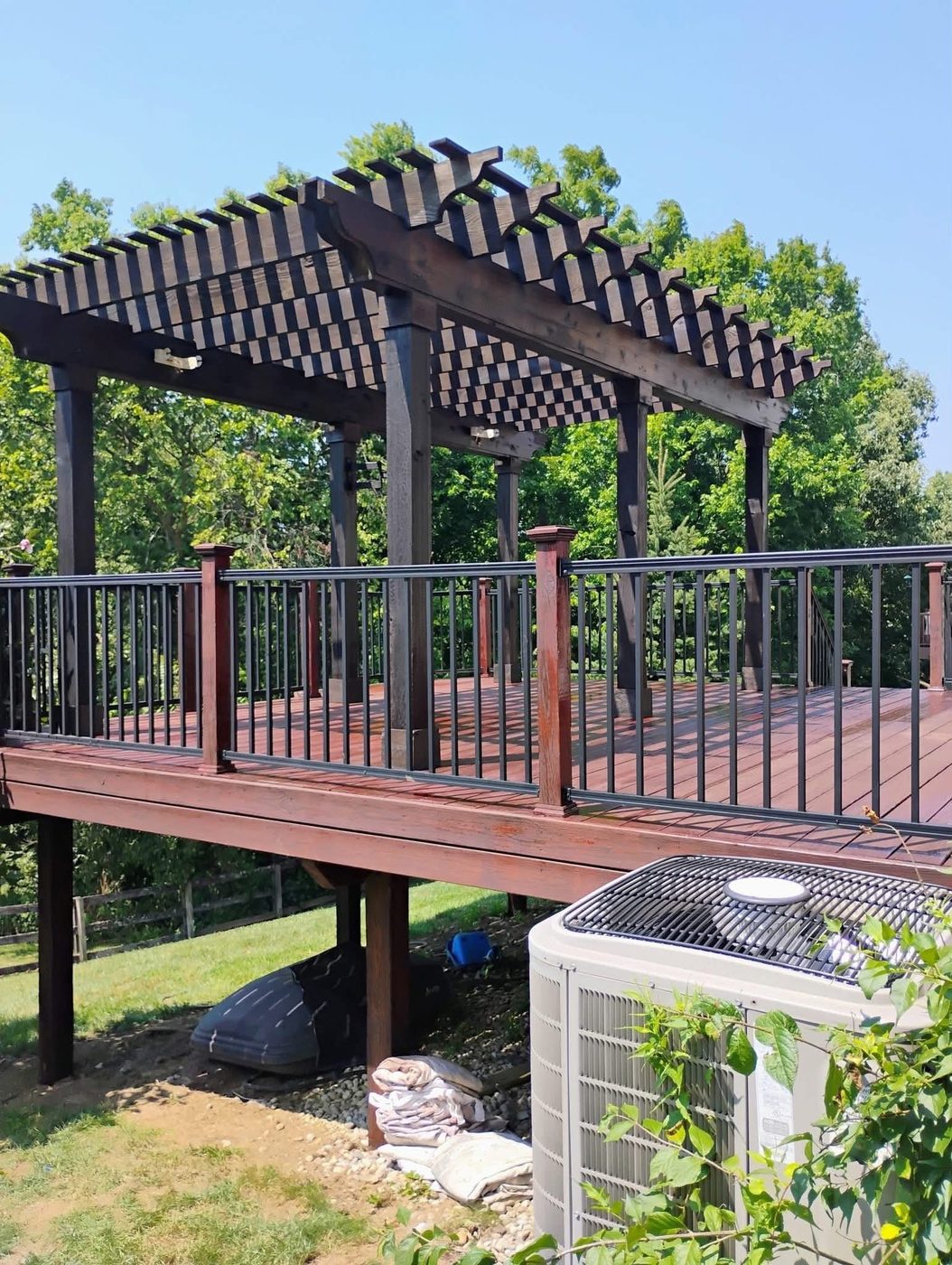 Raised deck and pergola stained deep reddish brown with black railings