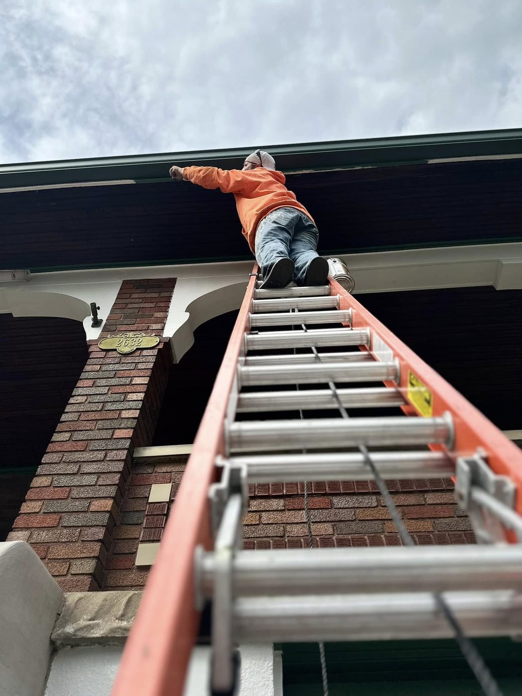 Dennis Kappes reaching to paint a fascia board from the top of an extension ladder