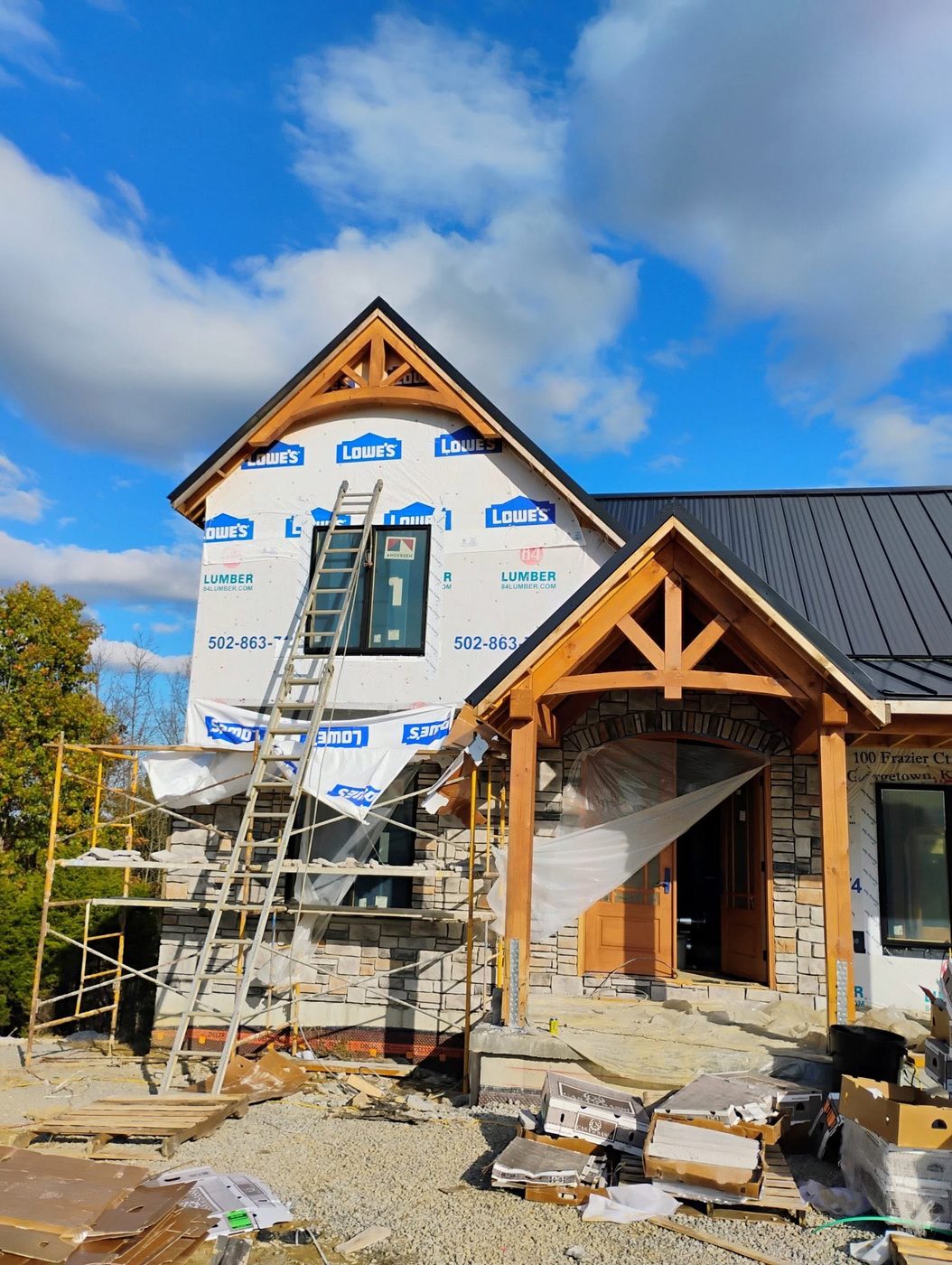 Stone and timber home under construction with scaffolding and a ladder