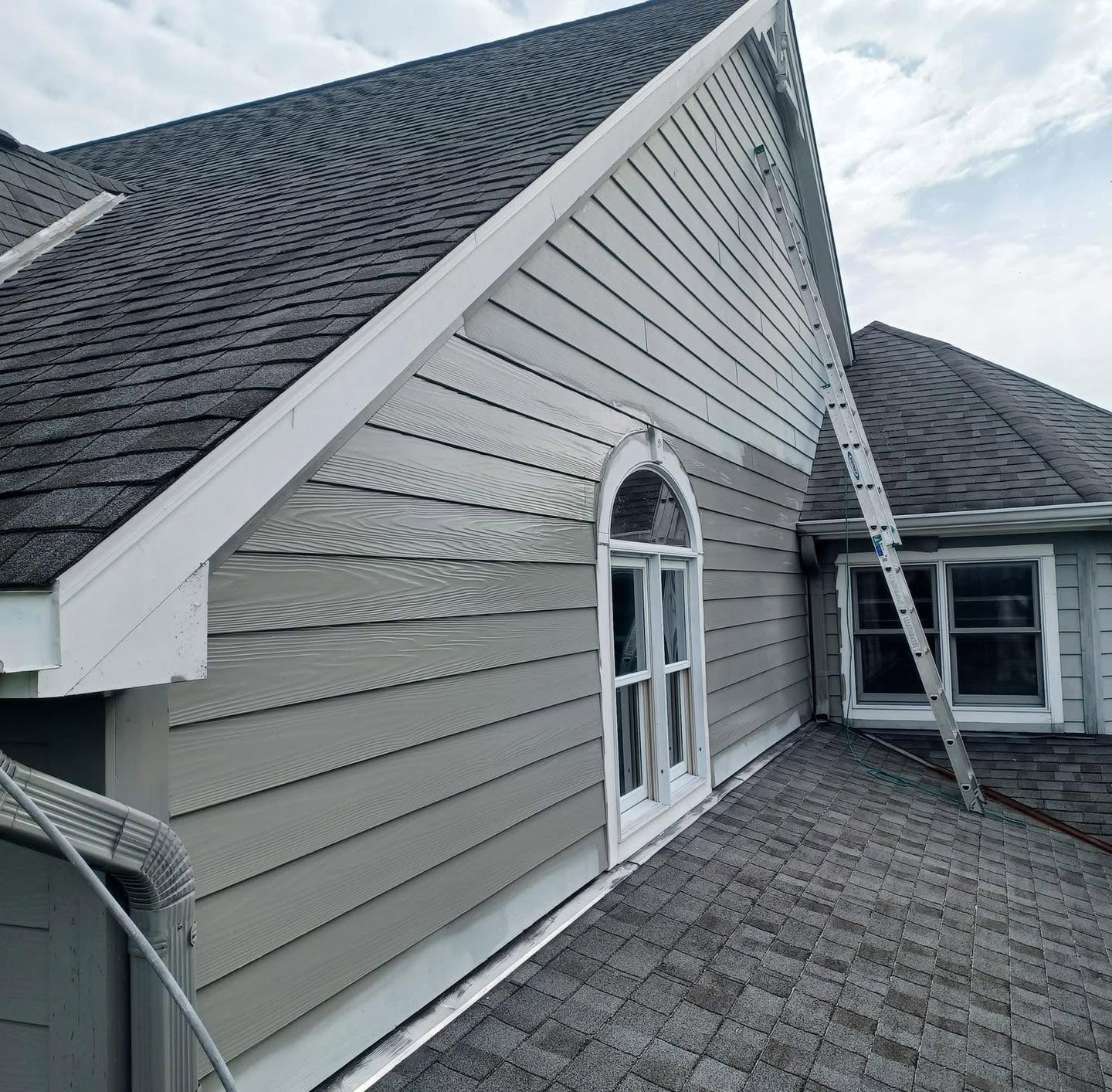 A repainted gable and siding on a two-story home, with an extension ladder still in place.